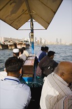 Commuter passengers on Abra water taxi on the Creek with Twin Towers shopping mall and skyline behind