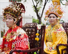Women in Chinese costume carried in parade celebrating local temple.