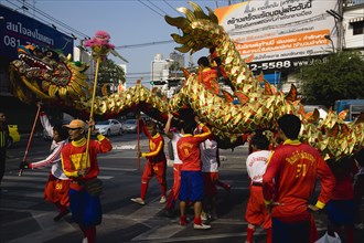 young men in costume carry Dragon in parade celebrating local Chinese temple on New Road first paved road in the city.