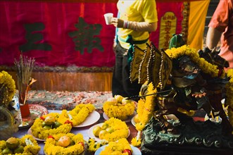 Offerings on table with embroidered panel behind carried in parade celebrating local temple.