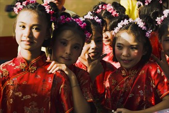 High School girls in Chinese Cheong sam dress in parade celebrating local temple.