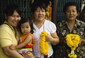 Four female generations of family with floral garlands to celebrate the annual blessing of local temple.