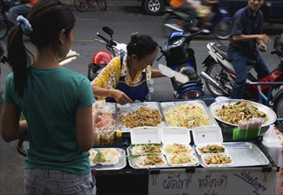 Street vendor and daughter sell take away Pad-thai the national fried noodle classic dish.