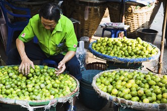 stall holder displaying limes in Chinatown market.