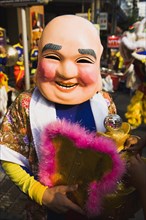 Member of dance troupe with papier mache character head and fan for Chinese New Year show.