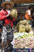 Thai man selling Durian fruit from cart.