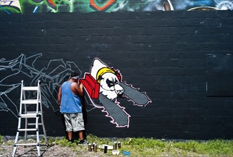 Graffiti artist painting wall.
