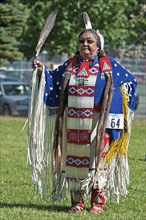 Blackfoot dancer in blue cape trimmed withotter fur and porcupine quill apron holding a feather fan in the Women's Traditional Dance at the Blackfoot Arts & Heritage Festival Pow Wow organized by Park...