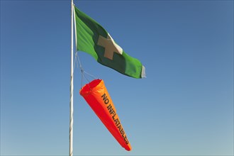 Safety flags. White Cross on Green Flag signalling First Aid Point. Orange No Inflatables windsock.