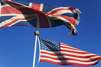 British and United States of America flags flying against a blue sky.