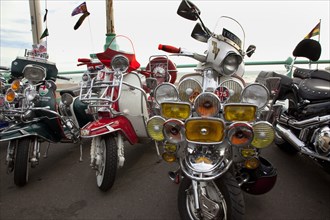 Elaborately decorated Mopeds on Madeira Drive during motorbike festival.