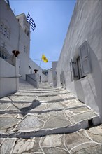 Portrait format low angle photograph of a typical alley found only at Cyclades island complex with the church of Agios Spyridonas on the left hand side.