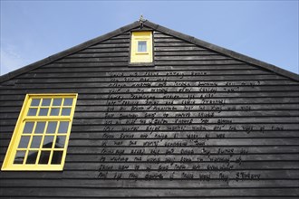 Detail of building gable wall with words carved from wood.