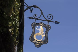 The Mermaid Inn pub sign against blue sky.