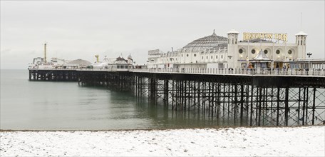 Pier during winter with snow on the beach.