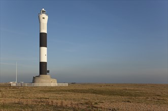 Black and white painted lighthouse on the shingle beach.
