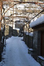 Little Papigko Village Narrow and frozen alley at the end of which a four weel drive bugy is noticeable