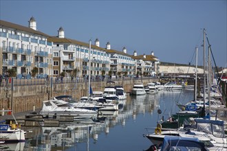 View over boats moored in the Marina with apartment buildings behind.
