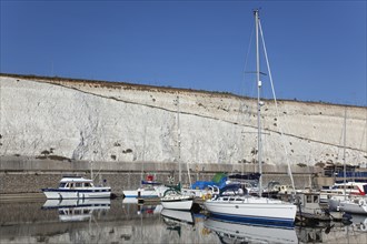 Boats moored in the Marina with chalk cliffs behind.
