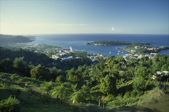 West Indies, Jamaica, Port Antonio, View over tree covered hillside towards waterside town and