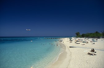 West Indies, Jamaica, Montego Bay, Sandy beach beside aquamarine water with people sunbathing and