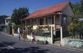 West Indies, Jamaica , Port Antonio, Roadside housing with veranda and walled garden. Boy and young
