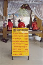 Thailand, Koh Samui , Chaweng Beach, Beach Massage with three women wearing red sat on benches