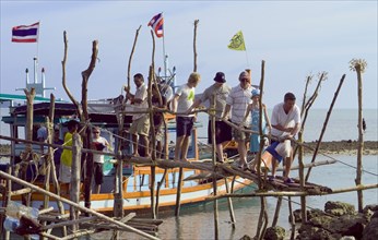 Thailand, Koh Samui, Thong Krutt fishing village. Tourists disembarking from a wooden boat after a