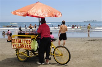 Mexico, Veracruz, Snack seller on Playa Villa del Mar with people on beach and in sea. Photo : Nick