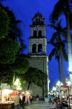 Mexico, Veracruz, Stalls in the Zocalo with the cathedral bell tower behind at night with