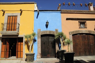 Mexico, Bajio, San Miguel de Allende, Colourful house facades on paved street with plant pots on