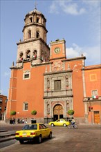 Mexico, Bajio, Queretaro, The church of San Francisco brightly coloured exterior facade with taxis