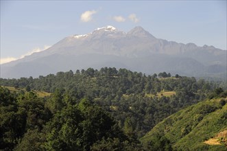 Mexico, Puebla, View of Ixtaccihuatl volcano with wooded parkland in foreground. Photo : Nick