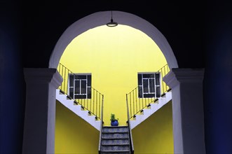 Mexico, Puebla, Looking into inner courtyard through archway in shadow towards yellow painted wall