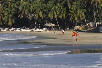 Mexico, Oaxaca, Puerto Escondido, Playa Marinera with couple walking along shore line of boats