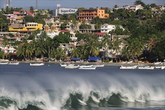 Mexico, Oaxaca, Puerto Escondido, Playa Principal Breaking waves and boats overlooked by buildings
