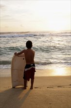 Mexico, Oaxaca, Puerto Escondido, Playa Zicatela Young body boarder standing on beach looking out