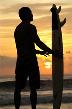 Mexico, Oaxaca, Puerto Escondido, Surfer and board silhouetted at sunset on Playa Zicatela. Photo :