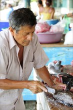 Mexico, Oaxaca, Puerto Escondido, Playa Principal Man preparing fresh fish in the market.. Photo :