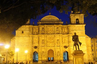 Mexico, Oaxaca, Baroque exterior facade of cathedral at night part framed by tree branches with