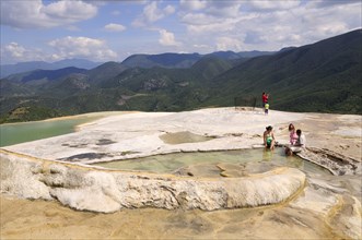 Mexico, Oaxaca, Hierve el Agua, Tourists beside limestone pools and looking out over surrounding