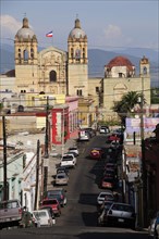 Mexico, Oaxaca, View along street lined with parked vehicles towards church of Santo Domingo. Photo