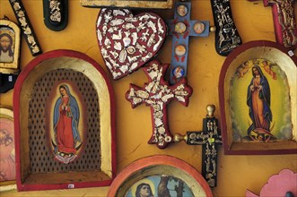 Mexico, Michoacan, Patzcuaro, Religious kitsch art displayed on yellow painted wall. Photo : Nick