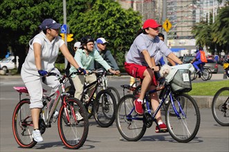 Mexico, Federal District, Mexico City, Cyclists on Reforma one carrying small dog in basket on