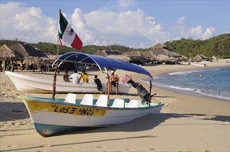 Mexico, Oaxaca, Huatulco, Fishing boats pulled up in front of beach shacks on Bahia San Agustin.