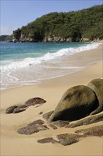 Mexico, Oaxaca, Huatulco, Bahia Chahue Rocks and deserted sandy beach with surf breaking on shore