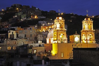 Mexico, Bajio, Guanajuato, Church of San Francisco at night with barrios on hillside beyond. Photo
