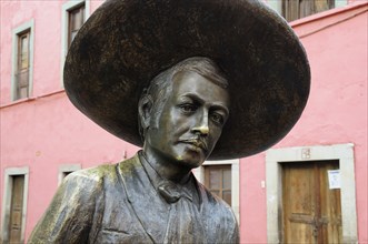 Mexico, Bajio, Guanajuato, Bronze statue of Charro singer Jorge Negrete with pink painted building