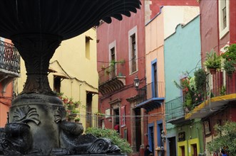 Mexico, Bajio, Guanajuato, Partly seen fountain in foreground of colourful buildings in the Plaza