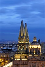Mexico, Jalisco, Guadalajara, Cathedral domed roof and bell towers at night with city spread out